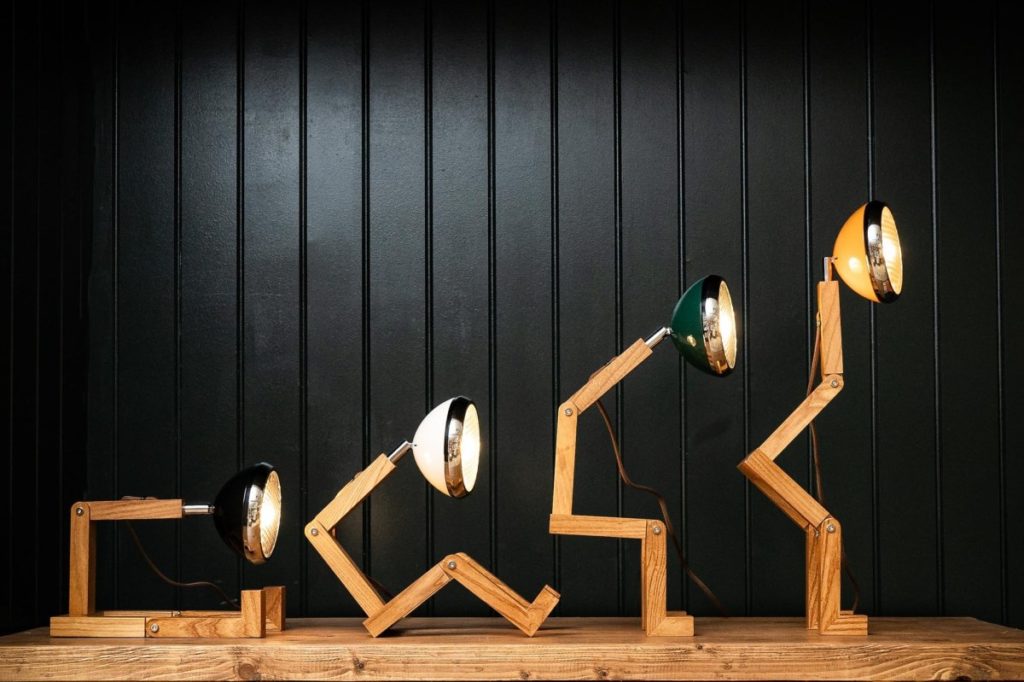 Lampada di legno e alluminio a forma di omino snodabile. La lampada si ispira ai fari delle vecchie amate vespe Piaggio.